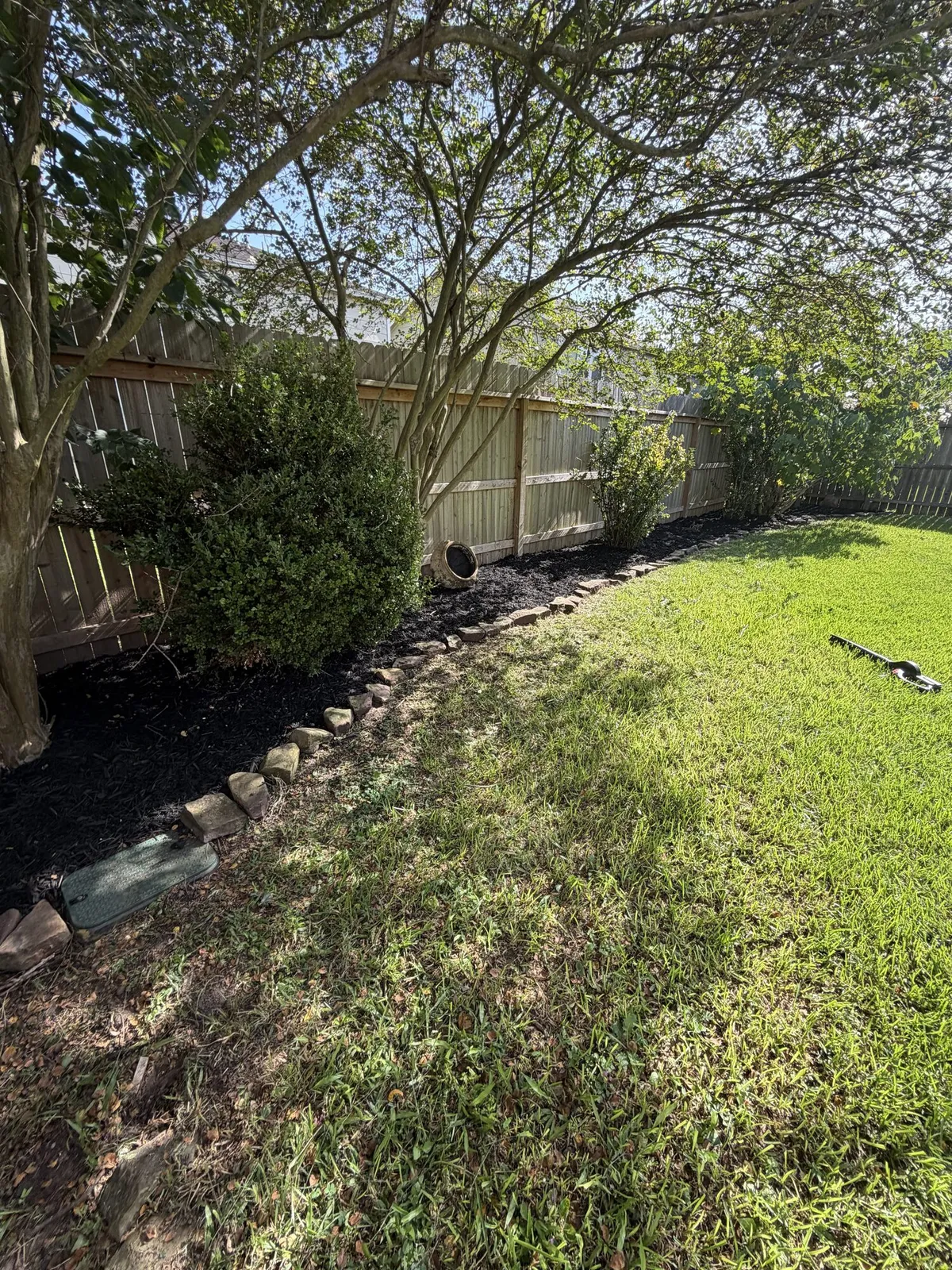 Fresh mulch bed along a backyard fence