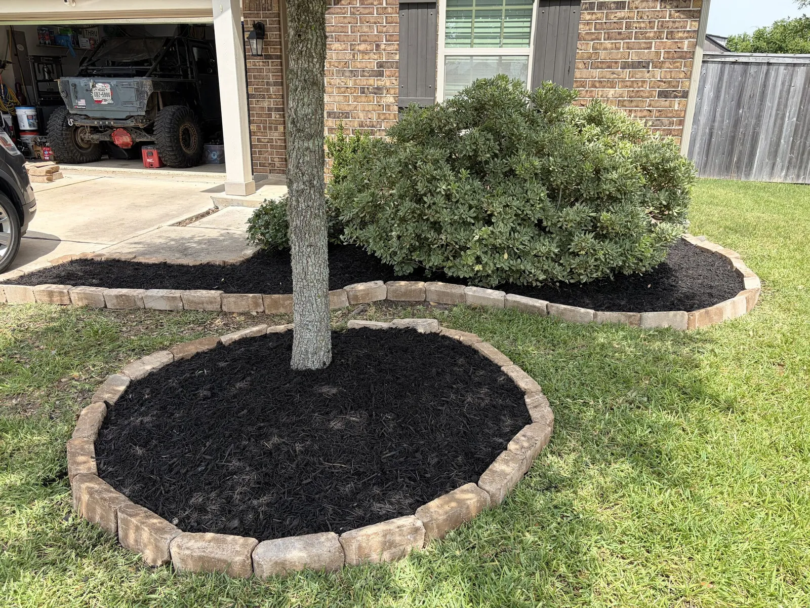 Stone ringed mulch bed around a front yard tree
