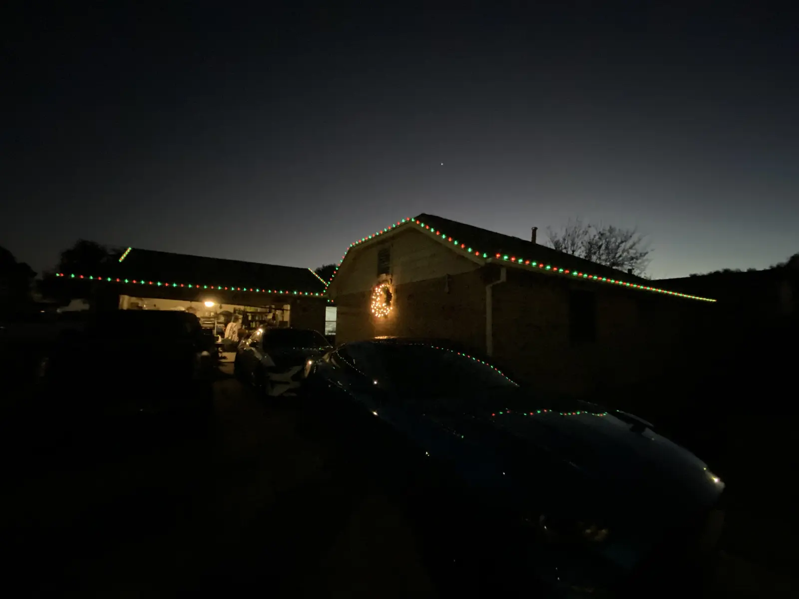 Red and green Christmas lights along a roofline at night