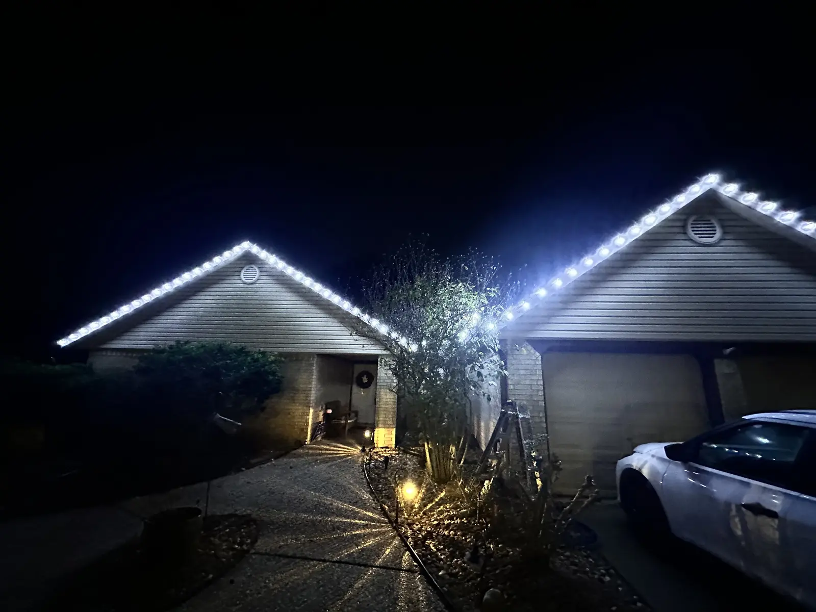 White Christmas lights along a garage roofline at night